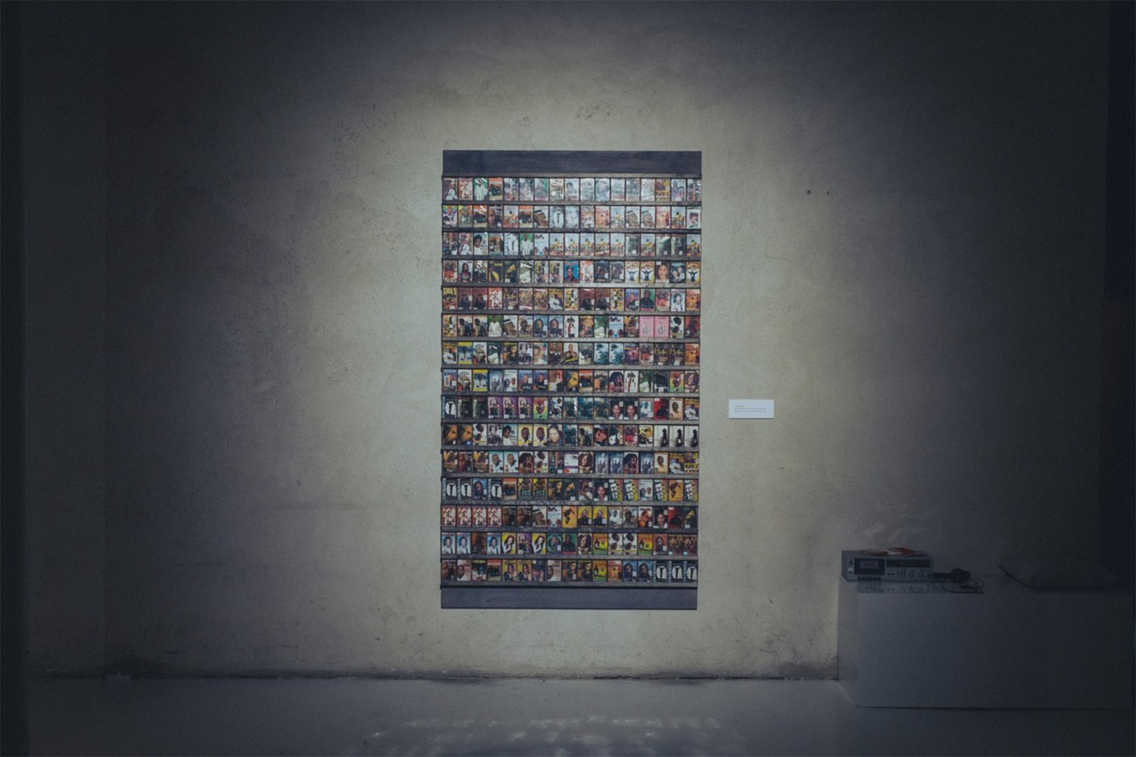 A grey wall with an artwork made with many pictures on it