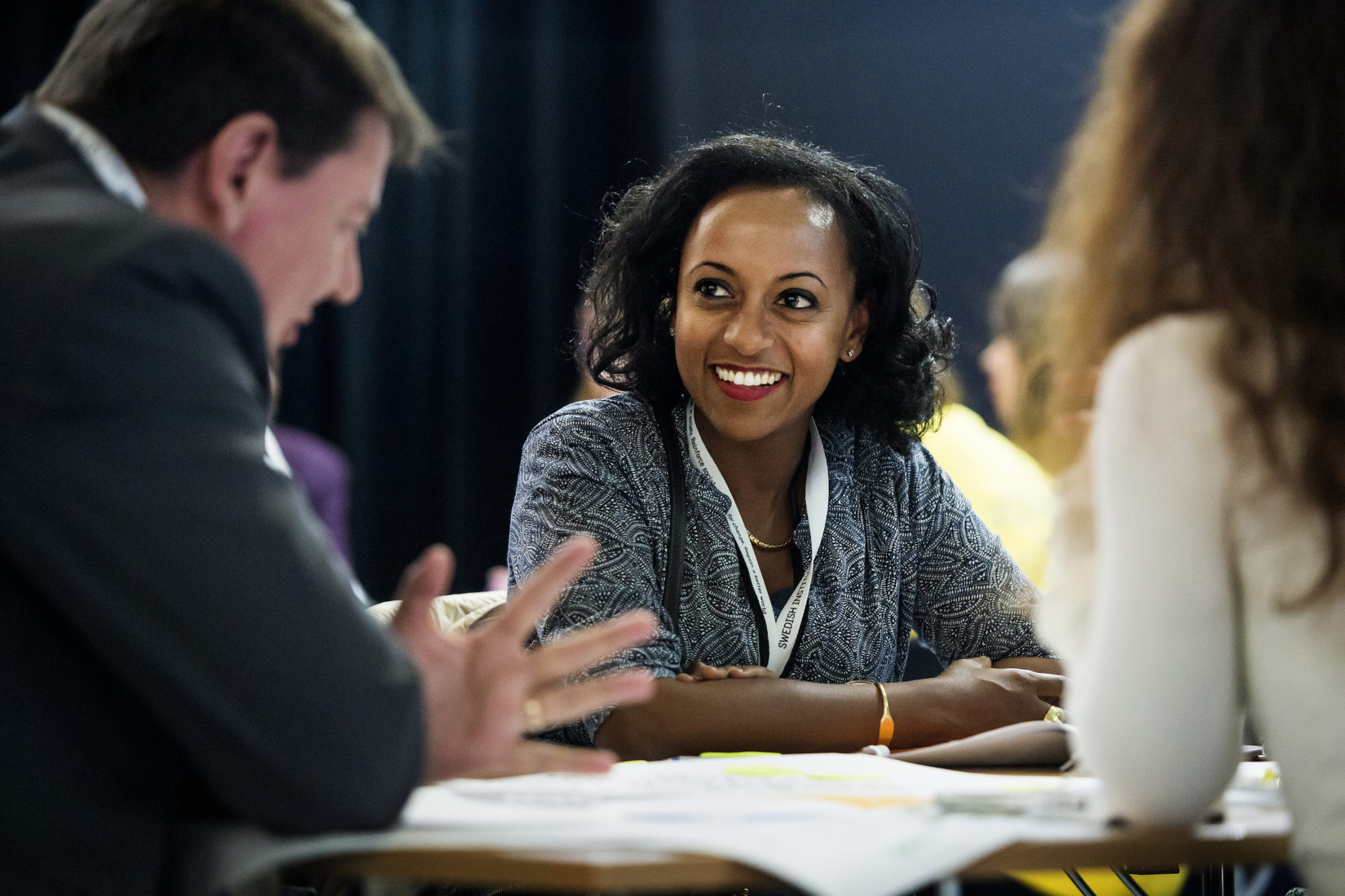 Woman sitting at a table listening to a man talking. 