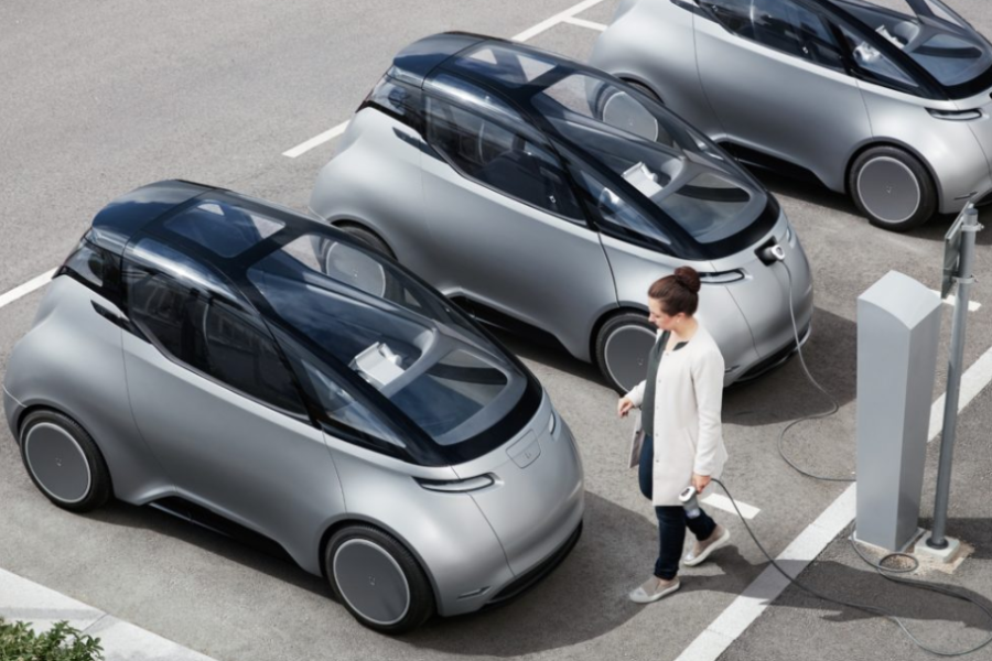 En kvinna går med en laddsladd på en parkeringsplats fram till en väldigt annorlunda bil. Uniti, en bil som sägs vara miljövänlig eller hållbar. Bilen är lättvikt och eldriven, gjort av komposterbara material och energi- och resursoptimerad. Fotograf: Karl-Fredrik von Hausswolff