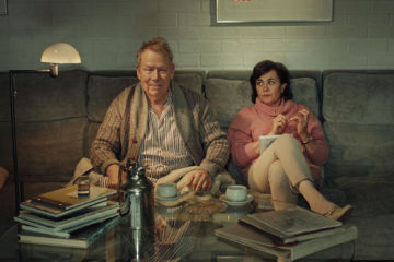Elderly couple sitting on the sofa drinking coffee
