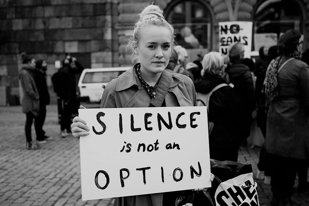 Girl with a sign saying Silence is not an option