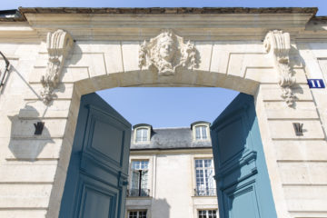 De blå dörrarna till Svenska institutet i Paris står på vid gavel, i bakgrunden skymtar man det vita stenpalatset.