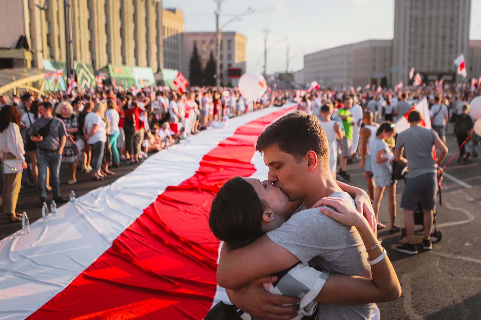 Ett ungt par kysser varandra framför den vitröda flaggan under de folkliga protesterna i Minsk