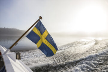 En svensk flagga på en båt vajar i vinden..