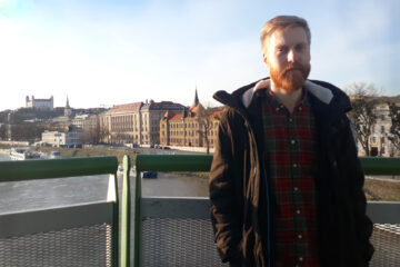 En man står på en bro med staden i bakgrund