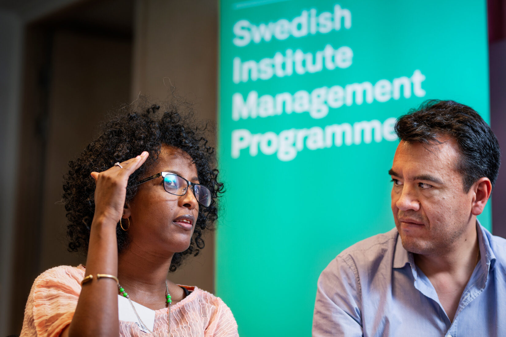 Close up shot of two persons discussing with one another, roll-up in the background