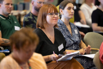 Foto på personer som sitter och lyssnar under en konferens.