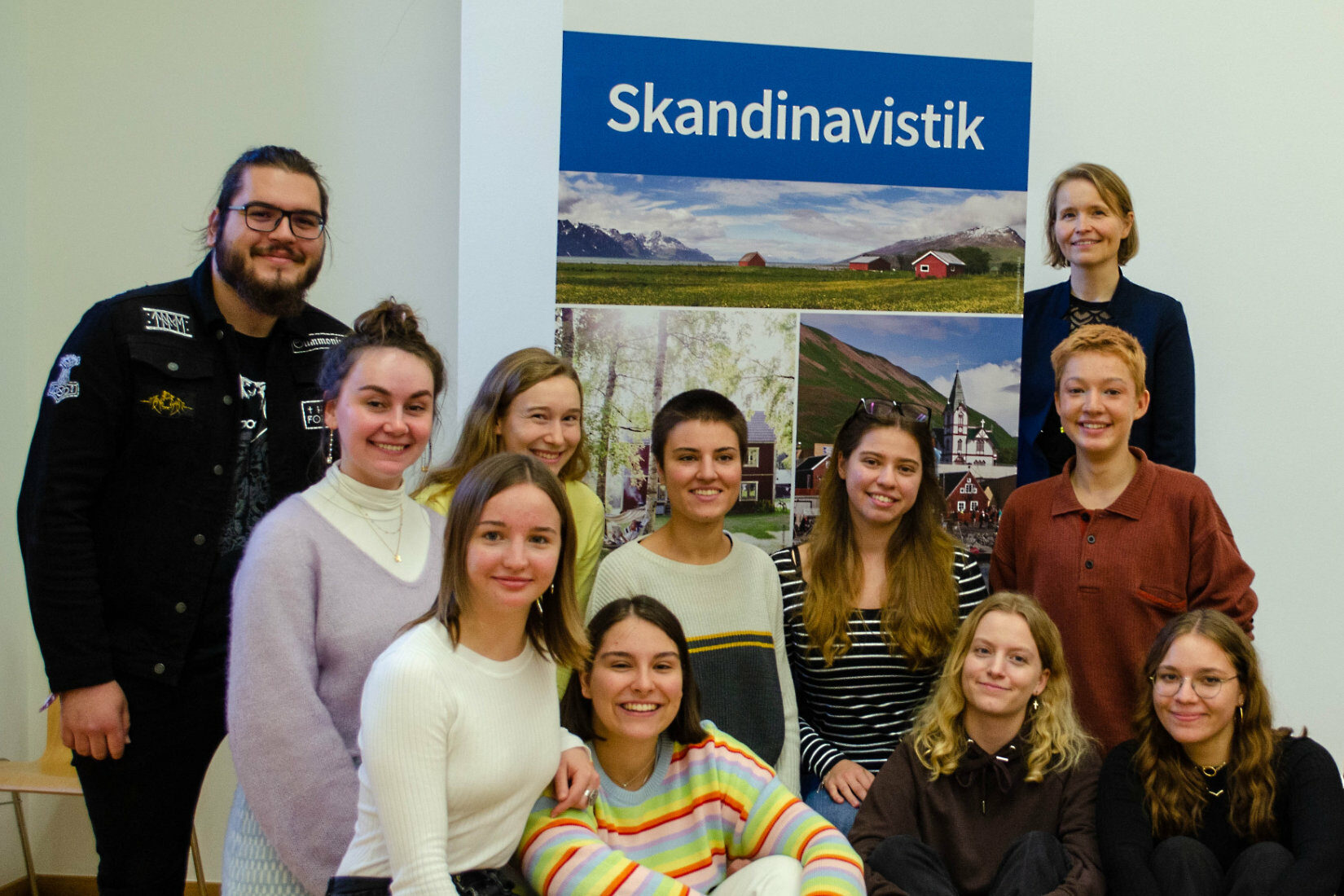 10 studenter och en lärare står framför en roll-up med texten Skandinavistik.