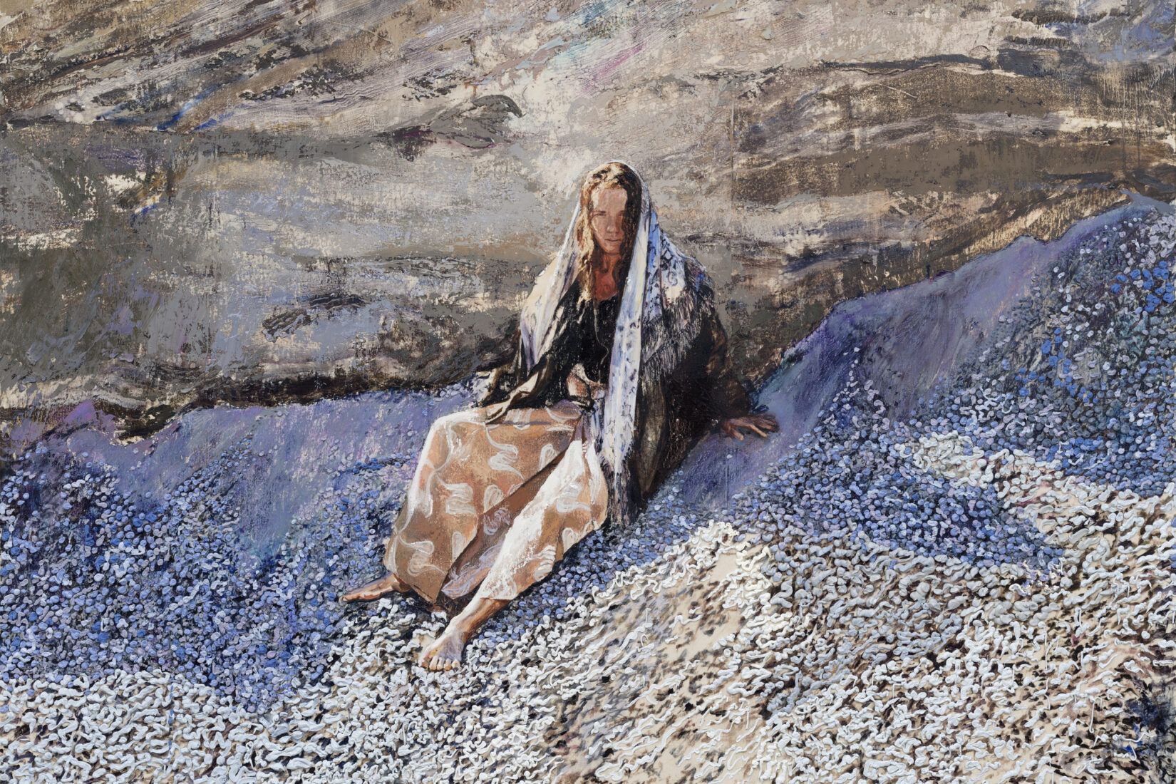 Kvinna med en sjal runtom sig sitter på en strand med musslor.