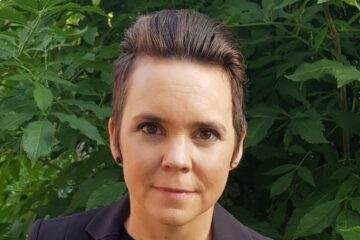 Porträtt av Sara Lövestam utomhus med grön buske i bakgrunden