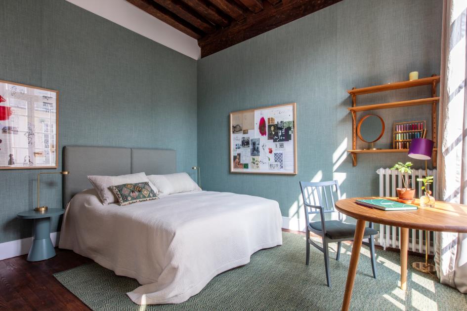 Foto på ett av gästrummen. En säng och gröna tygväggar.