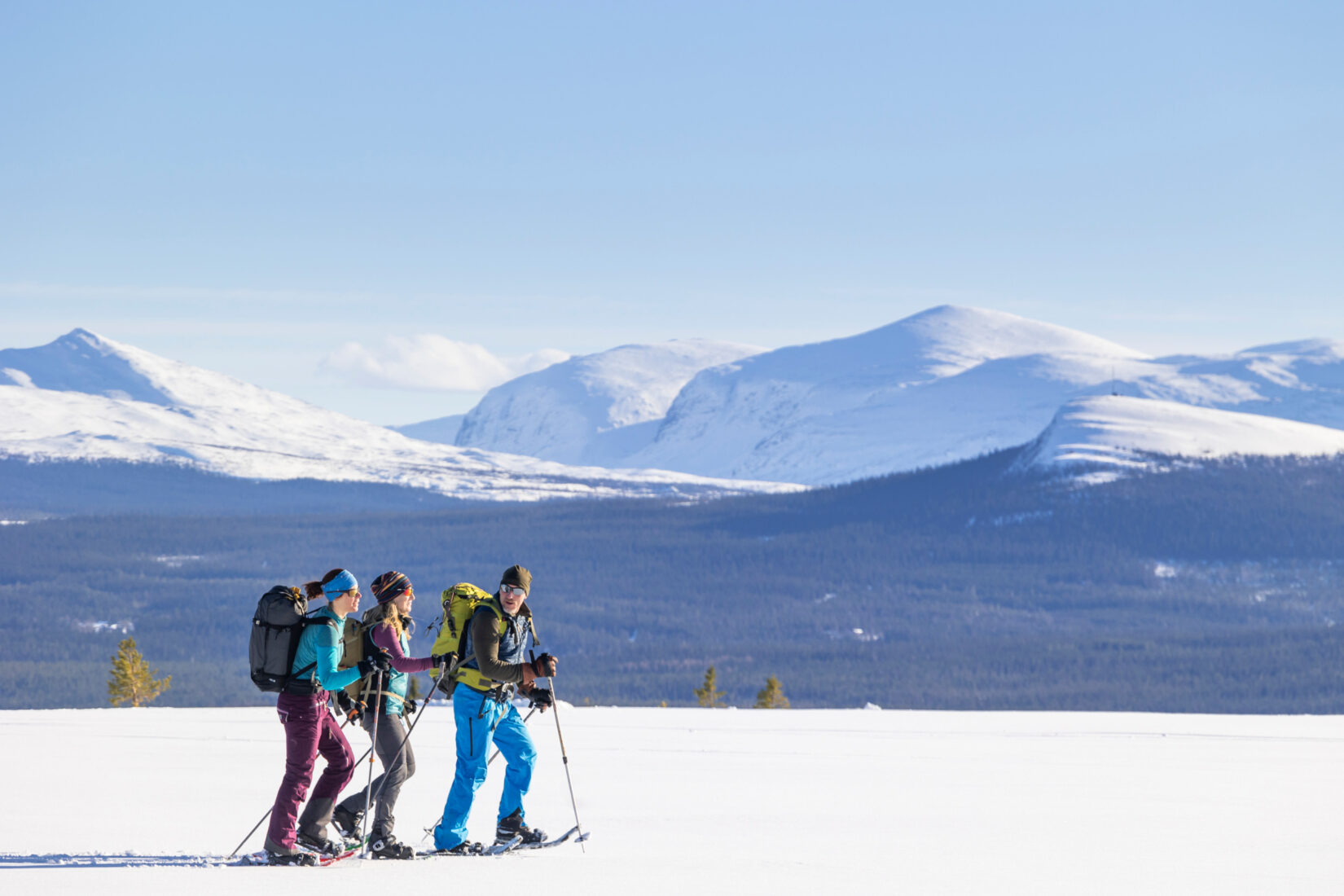 Tre personer på en promenad i ett snötäckt fjällandskap i norra Sverige.