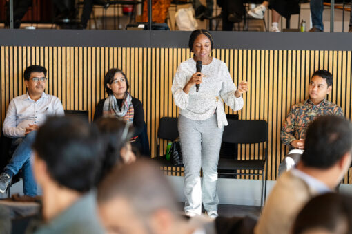 Woman staning in front of peers holding a mic