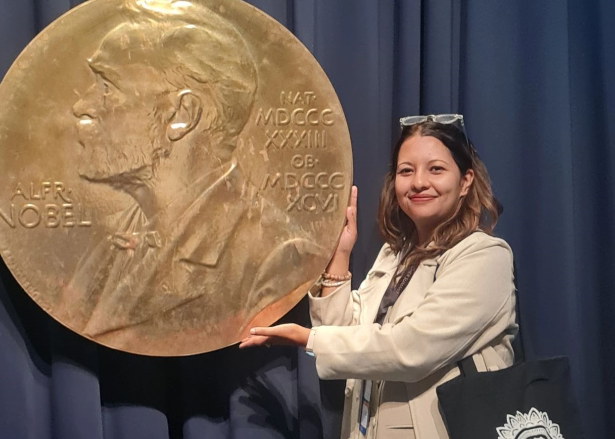 Woman posing next to a large sized Nobel prize medal