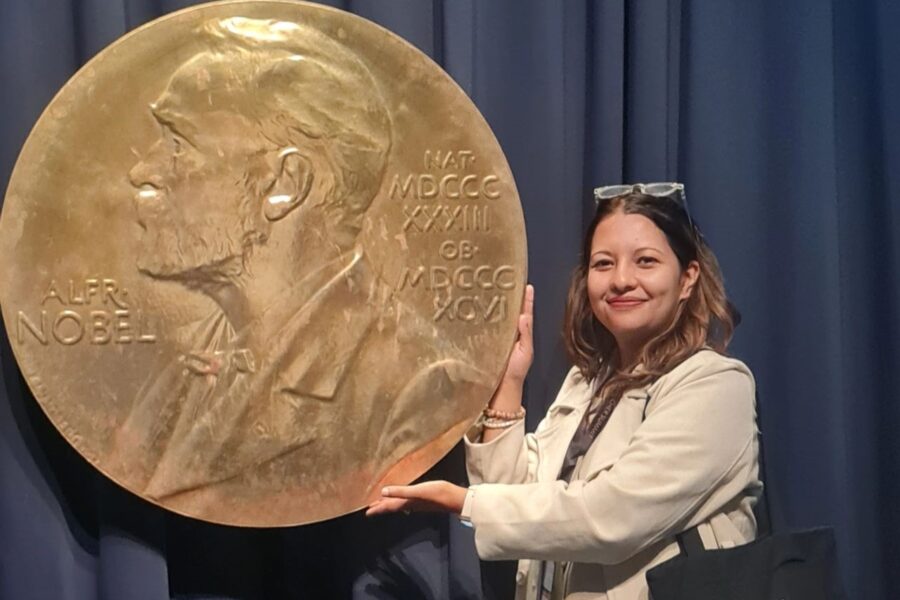 Woman posing next to a large sized Nobel prize medal