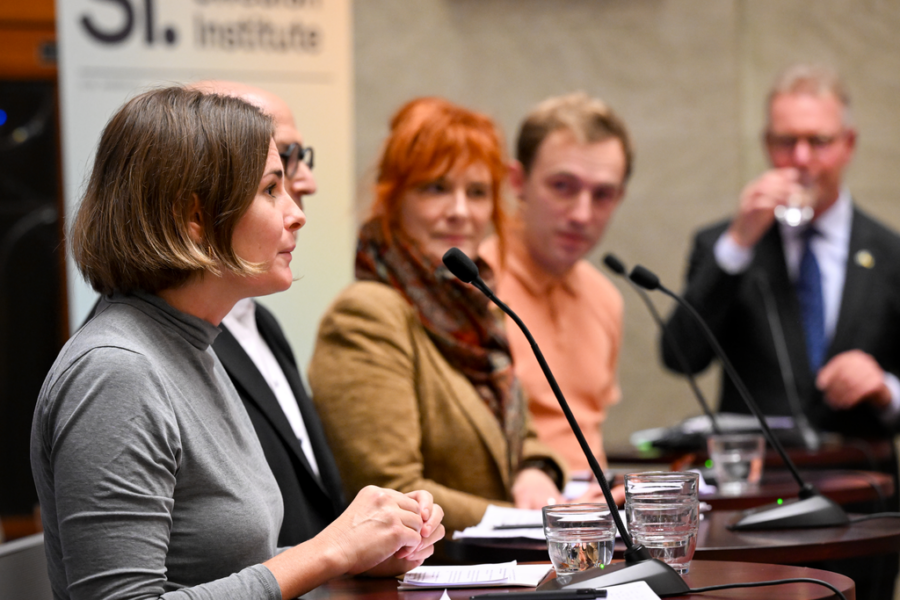 Paneldeltagare står runt ett bord och för en diskussion.