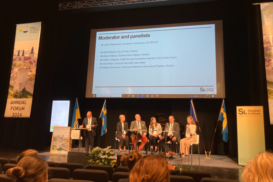 En panel för ett samtal på en stpr scen. På scenen finns två svenska flaggor, en EU-flagga samt en ukrainsk flagga.