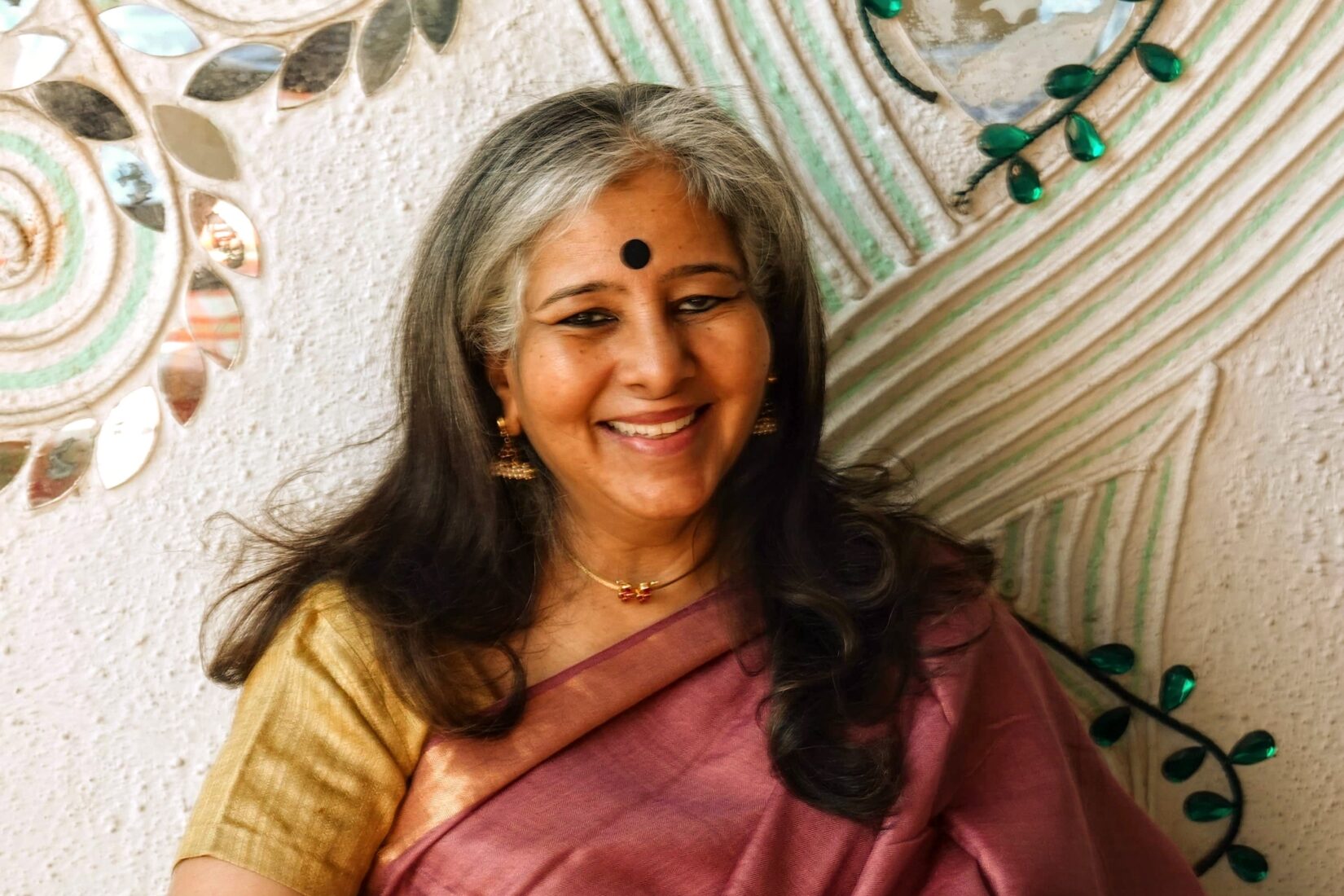 Woman in long hair and a golden and pink outfit.