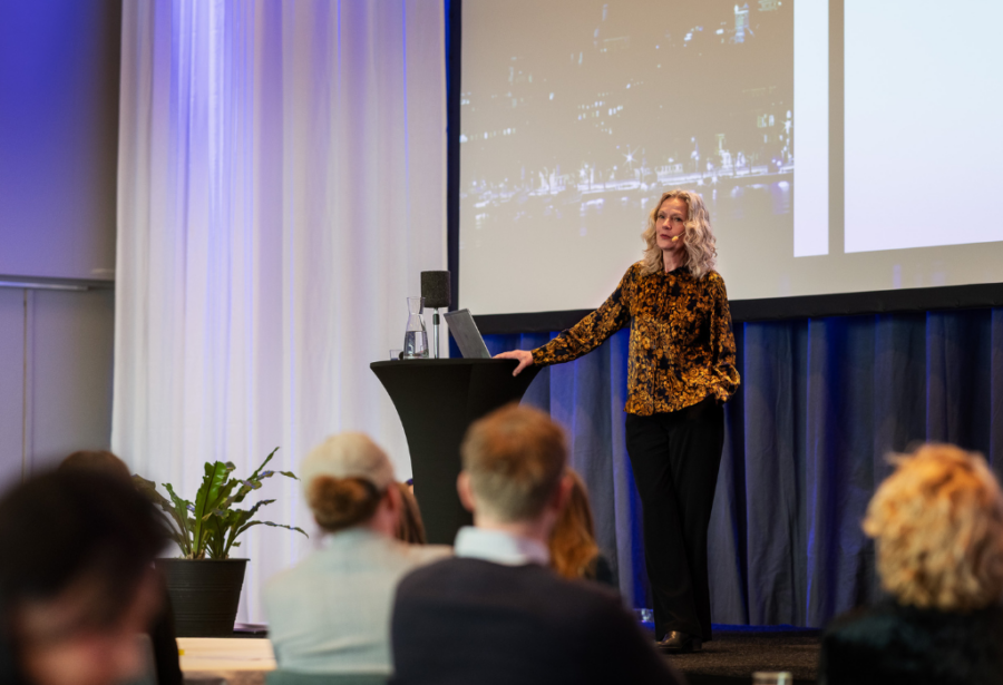 250508_DSC2576-1©Malin Nerby_SI A woman standing on a stage speaking to an audience.