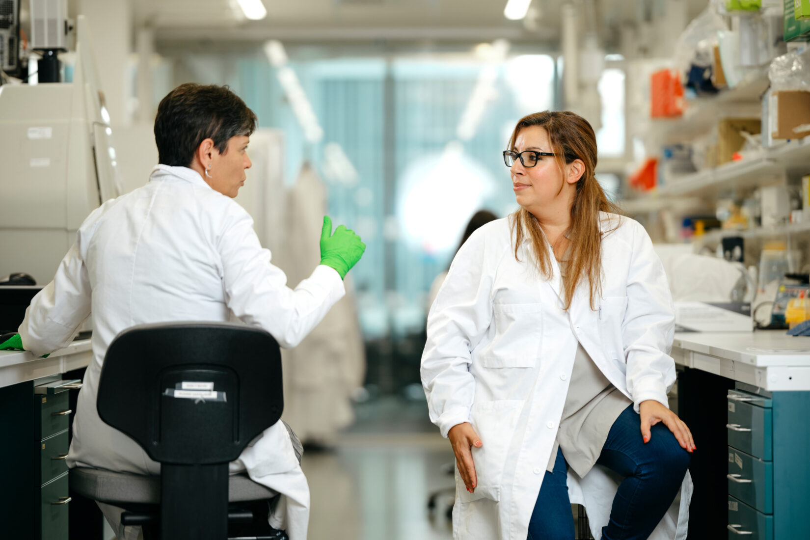 Två personer som arbetar på ett laboratorium sitter och pratar.
