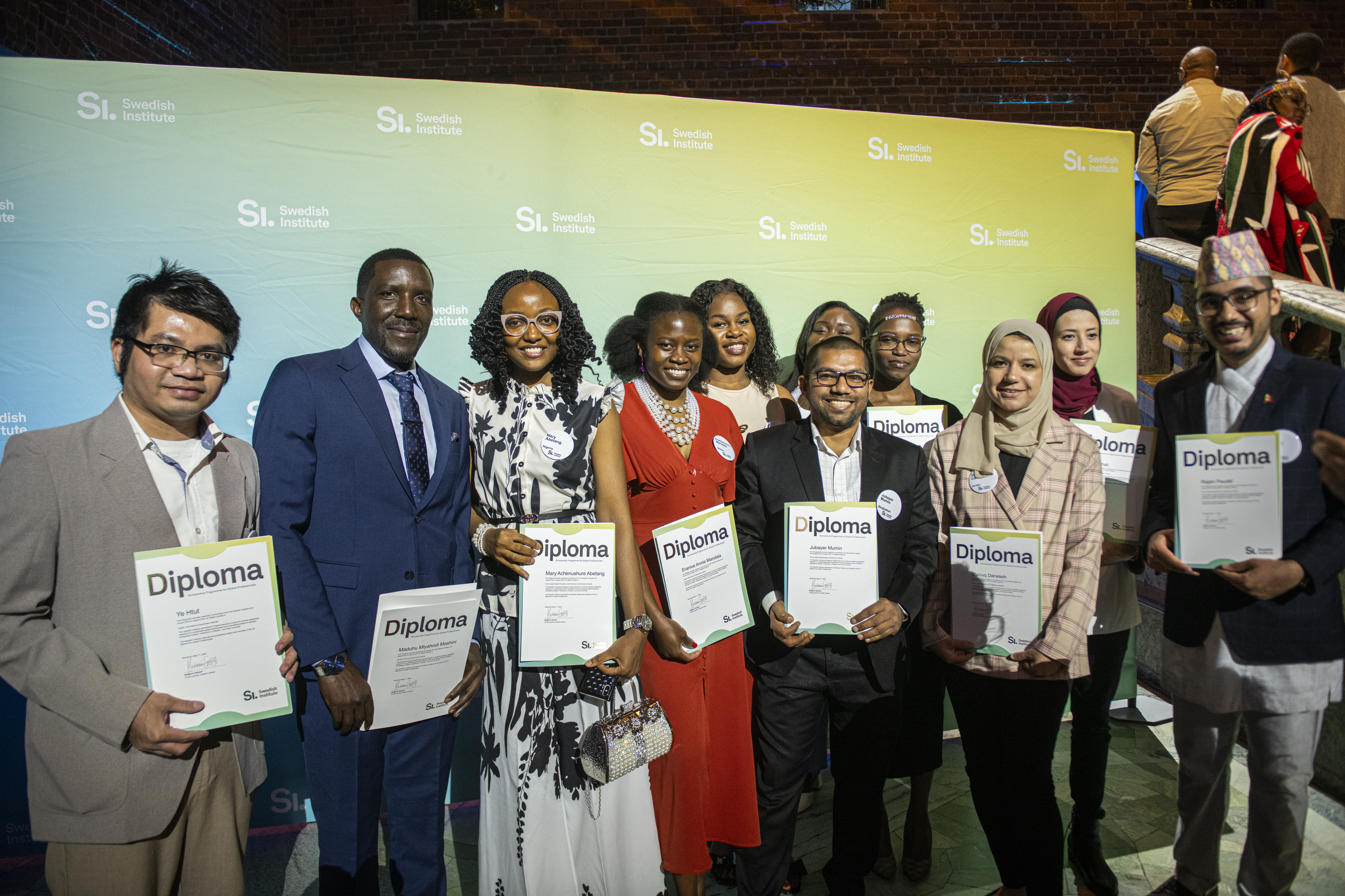 A group of graduates holding their diplomas and posing for the camera.